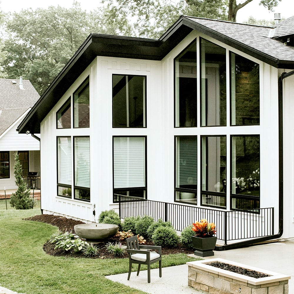 A modern home featuring large windows and a spacious patio, showcasing contemporary architectural design.